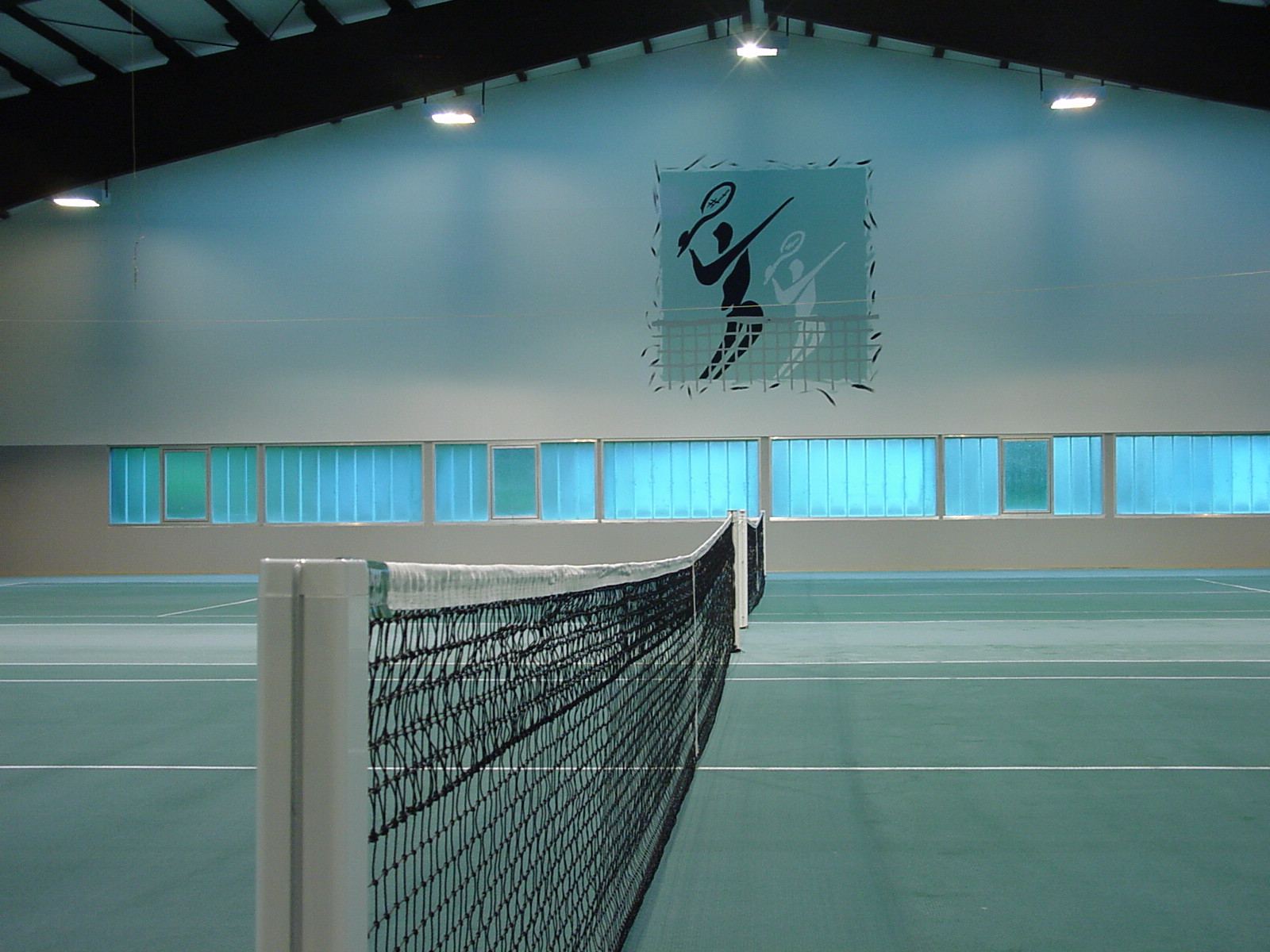 Innenansicht der 2-Feld-Tennishalle Westerheim mit Netz und Vereinslogo an der Wand